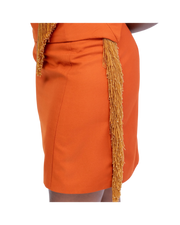 Orange skirt with gold fringe details on a white background