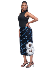 Woman wearing a black sleeveless top and a black and blue patterned skirt with white feather details on a white background