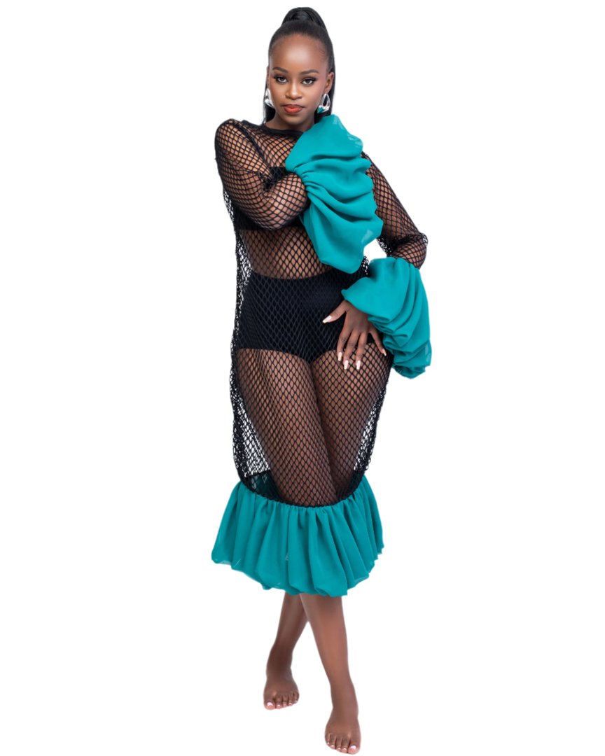 Woman wearing a black fishnet top and teal skirt with green jacket on a white background